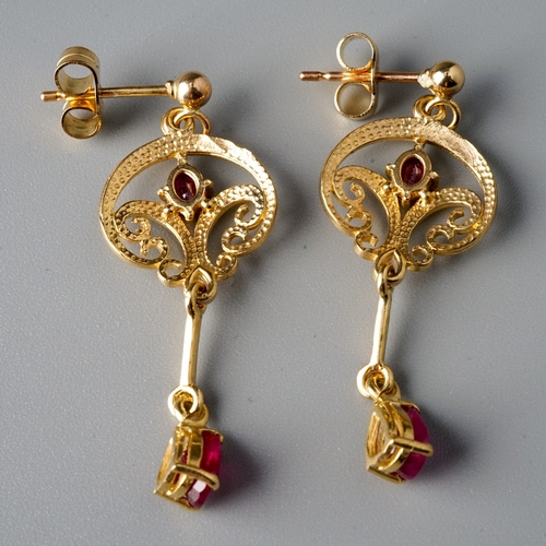 8 - A pair of 9ct yellow gold and ruby drop earrings, the scrolling openwork suspending a knife-edge dro... 