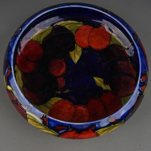 439 - A William Moorcroft shallow bowl in the Wisteria pattern on a shallow bowl with inverted rim, blue s... 