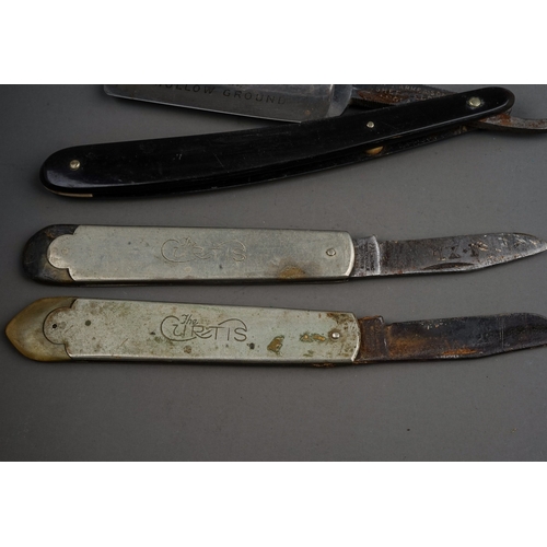 702 - A tin containing a small collection of pocket knives and cut throat razors, including a hallmarked s... 