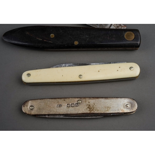 702 - A tin containing a small collection of pocket knives and cut throat razors, including a hallmarked s... 