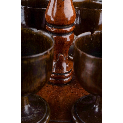 777 - An early 19th century turned treen set of six egg cups on stand, central handle, egg cups sitting on... 