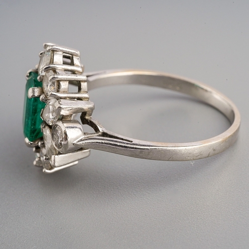 15 - A platinum emerald and diamond cluster ring, set with an emerald-cut emerald approx 7.00mm x 5.35mm ... 