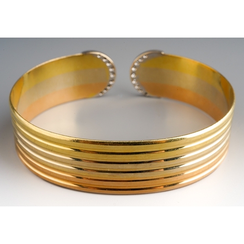 19 - An 18ct tri-colour gold and diamond torque bangle, grooved decoration with crescent terminals, each ... 