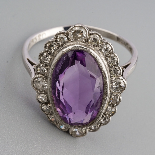 23 - An amethyst and diamond cluster ring, set with an oval shape amethyst, within a single and early bri... 