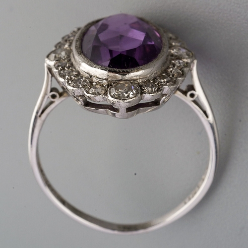 23 - An amethyst and diamond cluster ring, set with an oval shape amethyst, within a single and early bri... 