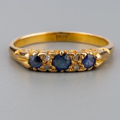 33 - An 18ct gold sapphire and diamond ring, three round cut sapphires with diamond chip spacers, size N,... 