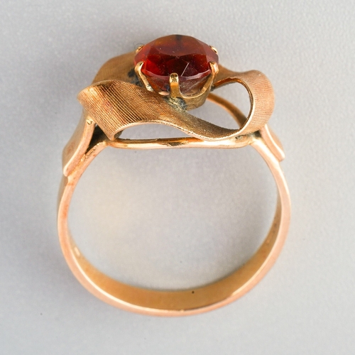 68 - A garnet dress ring, set with a circular shape mixed cut garnet, claw set, within a undulating textu... 