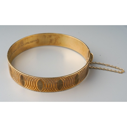 74 - 9ct gold bangle with etched detail and safety chain. Gross weight 20.8g