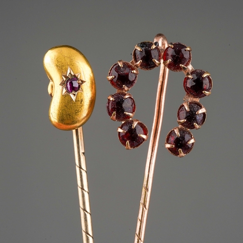 133 - Two tie pins to include a 15 ct bean shaped one set with a ruby chip and a yellow metal horse shoe o... 