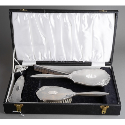 255 - An Elizabeth II cased silver four piece dressing table set, comprising hand mirror, two brushes and ... 