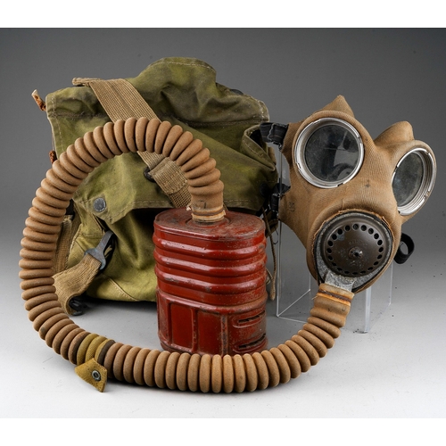 397 - A WW II gas mask, with painted red canister stamped 1940, with fabric covered face mask and tubing, ... 