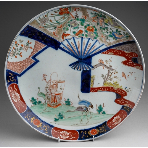 569 - A Japanese Meji Imari charger decorated with Scholar reading a scroll surrounded by cranes, motifs, ... 