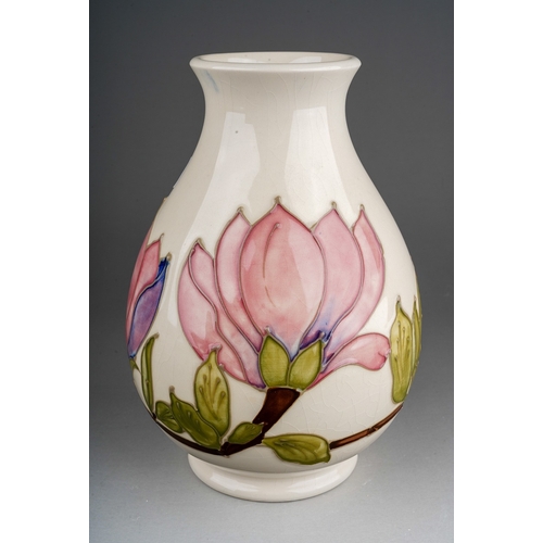 604 - A boxed Moorcroft pottery baluster vase decorated with magnolia design on an ivory ground, painted a... 