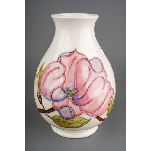 604 - A boxed Moorcroft pottery baluster vase decorated with magnolia design on an ivory ground, painted a... 