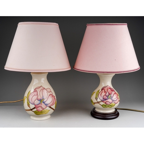 631 - Two Moorcroft pottery baluster table lamps decorated in a Magnolia design on an ivory ground, one wi... 