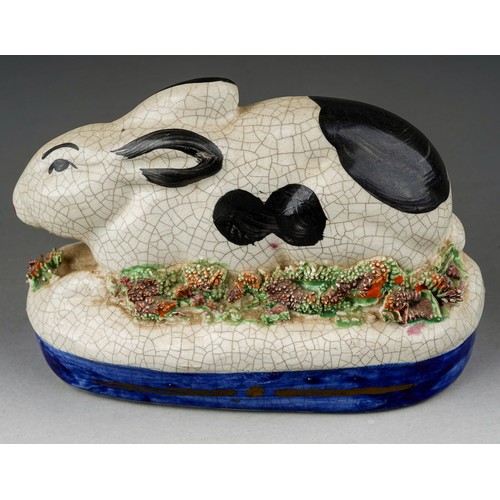 656 - A Staffordshire model of a crouching black and white rabbit on oval raised gilt heightened base, boc... 