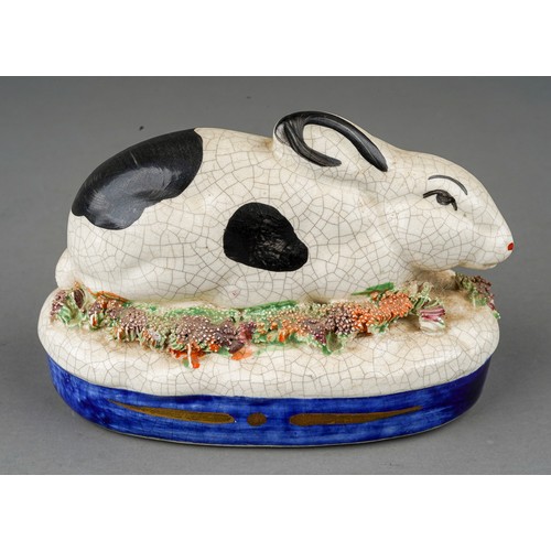 656 - A Staffordshire model of a crouching black and white rabbit on oval raised gilt heightened base, boc... 