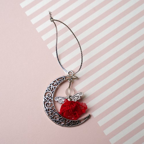 739 - An Angel charm attached to a metal moon, made using the lace from Lisa Snowdon’s red bra and silver ... 