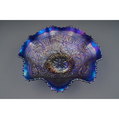 809 - An early 20th century American blue carnival glass wavy rimmed bowl, by Northwood, decorated in in t... 