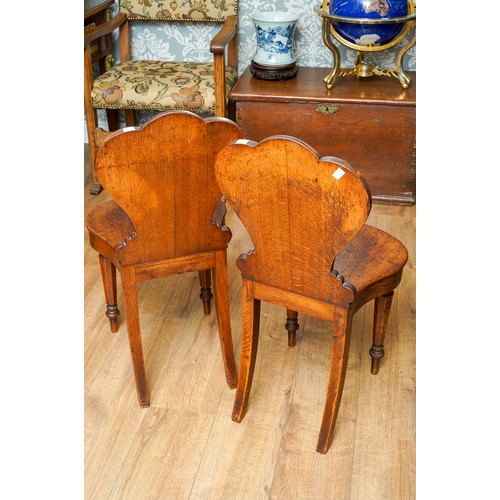 975 - A pair of Victorian oak hall chairs, the cartouche shaped back carved with coronet and scroll style ... 