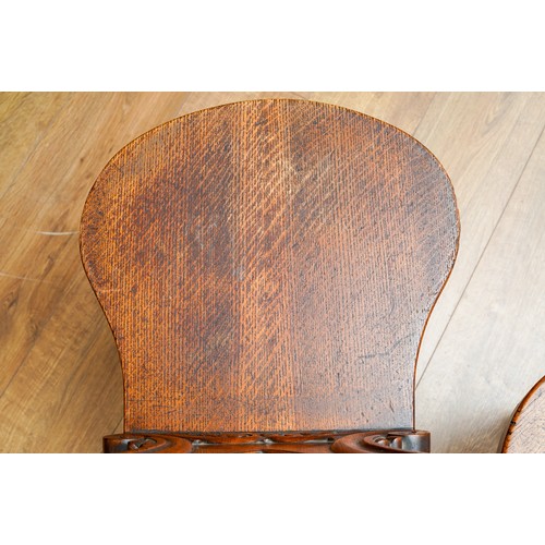 975 - A pair of Victorian oak hall chairs, the cartouche shaped back carved with coronet and scroll style ... 