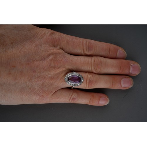 23 - An amethyst and diamond cluster ring, set with an oval shape amethyst, within a single and early bri... 