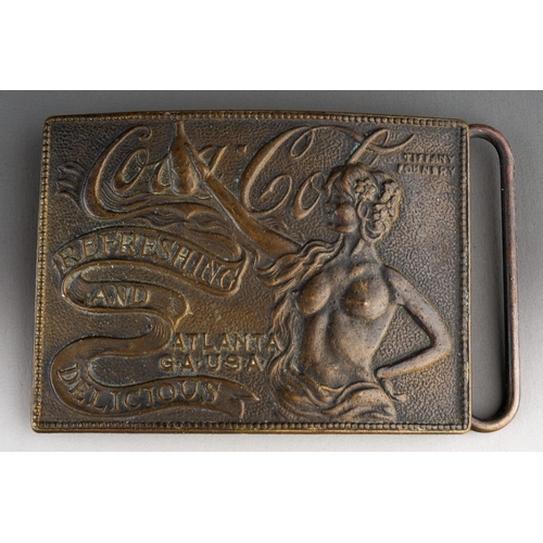 494 - Coca Cola: a Tiffany Studio New York Coca Cola belt buckle, the half length nude woman holding a bot... 