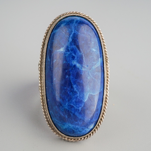 584 - A gem set ring. Set with an oval blue gemstone cabochon, rub over set within a rope twist border, re... 