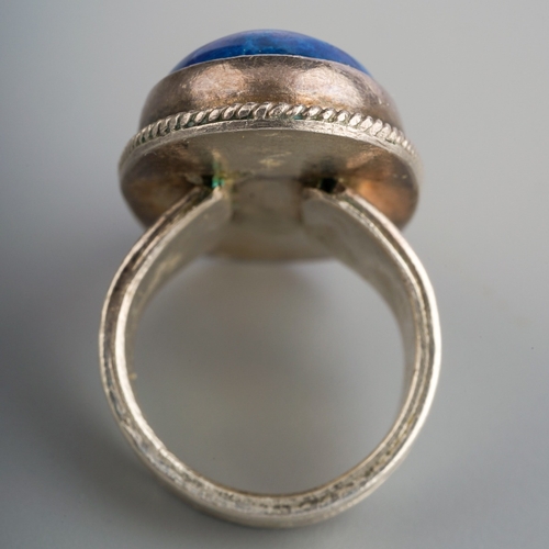 584 - A gem set ring. Set with an oval blue gemstone cabochon, rub over set within a rope twist border, re... 