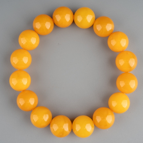 609 - A butterscotch amber bracelet comprising of sixteen spherical beads, 20.3 grams, together with Chine... 