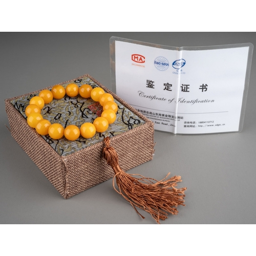 609 - A butterscotch amber bracelet comprising of sixteen spherical beads, 20.3 grams, together with Chine... 