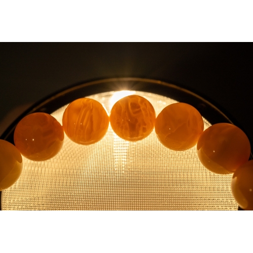 609 - A butterscotch amber bracelet comprising of sixteen spherical beads, 20.3 grams, together with Chine... 