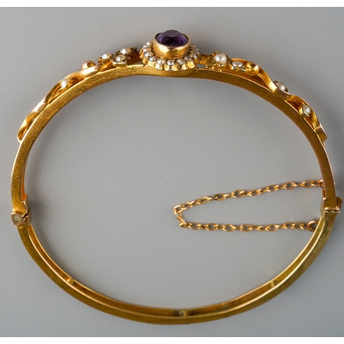 634 - An Edwardian bangle. The front set with an amethyst with seed and split pearls, inner diameter of ba... 