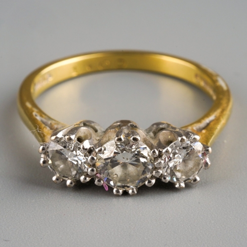 649 - An 18ct gold diamond three stone ring. Set with graduating round brilliant cut diamonds, within whit... 