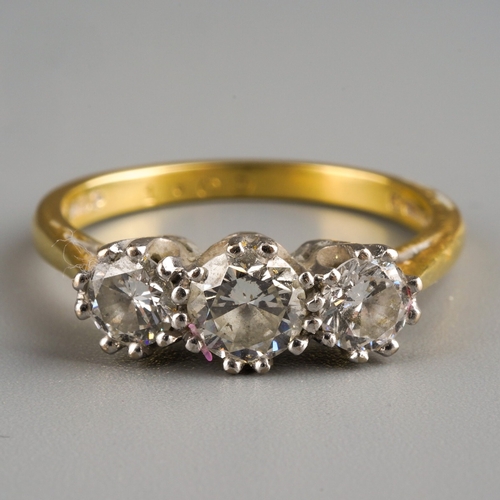 649 - An 18ct gold diamond three stone ring. Set with graduating round brilliant cut diamonds, within whit... 