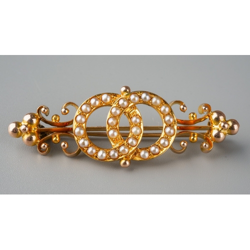 668 - An early 20th century split pearl bar brooch. The central split pearl detail with scroll design side... 