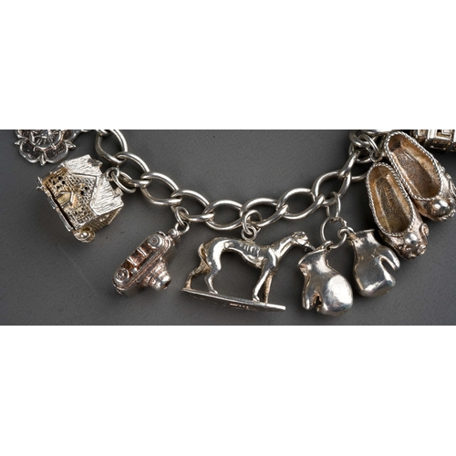 692 - A 20th century silver charm bracelet, with heart padlock and ten attached charms, gross weight 1.79o... 