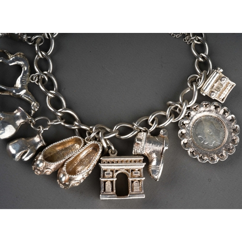 692 - A 20th century silver charm bracelet, with heart padlock and ten attached charms, gross weight 1.79o... 