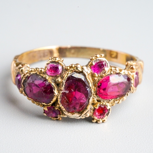 708 - A Georgian ring. Set with red glass, garnet and rubies, with beaded accents, to the engraved band, a... 