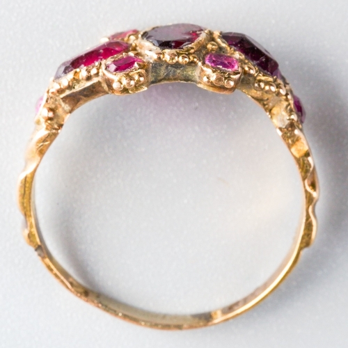 708 - A Georgian ring. Set with red glass, garnet and rubies, with beaded accents, to the engraved band, a... 