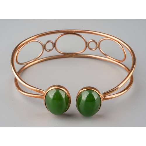 721 - A jade bangle. The torque design bangle set with two oval nephrite jade cabochons, rub over set, to ... 