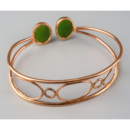 721 - A jade bangle. The torque design bangle set with two oval nephrite jade cabochons, rub over set, to ... 