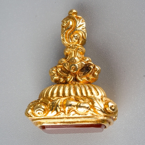 730 - A 9ct gold fob. Set with a carnelian, to the scroll embossed pedestal, hallmarked 9ct gold London 19... 