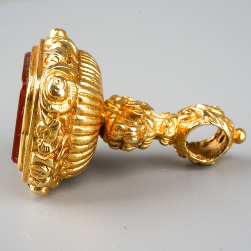 730 - A 9ct gold fob. Set with a carnelian, to the scroll embossed pedestal, hallmarked 9ct gold London 19... 