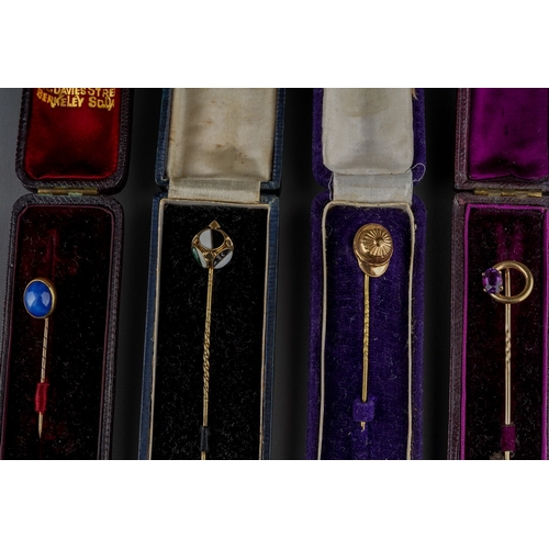 732 - A collection of four stickpins in box. To include a rolled gold novelty hat stickpin, a synthetic sa... 