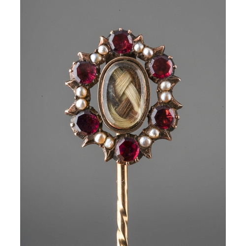 734 - A Victorian mourning stickpin. The central woven hair panel, within a garnet and seed pearl surround... 