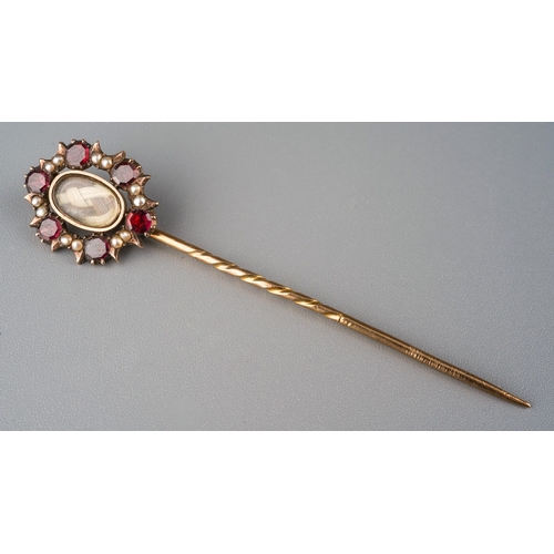 734 - A Victorian mourning stickpin. The central woven hair panel, within a garnet and seed pearl surround... 