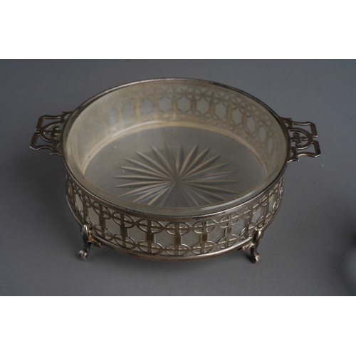 778 - A George V silver pierced circular butter dish holder, on four supports, opaque glass liner, the sil... 