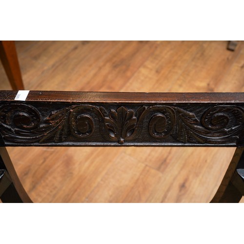 788 - A Savonarola X frame chair, carved back rail, arms and supports with floral decoration, upholstered ... 