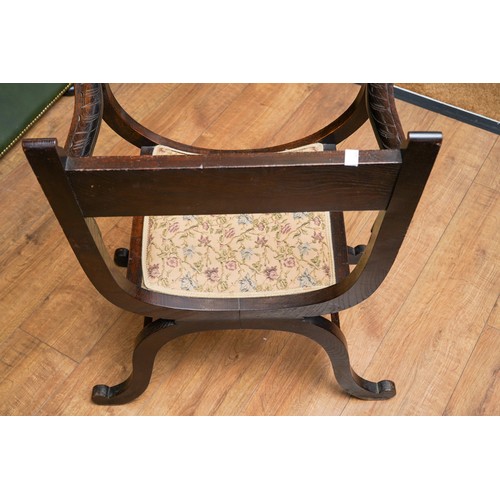 788 - A Savonarola X frame chair, carved back rail, arms and supports with floral decoration, upholstered ... 